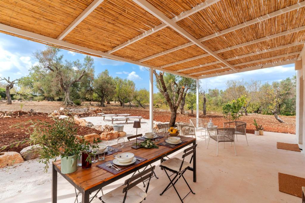 un patio extérieur avec une table et des chaises en bois dans l'établissement Trullo dell'Oleandro - Le Corti del Silenzio, à Ceglie Messapica