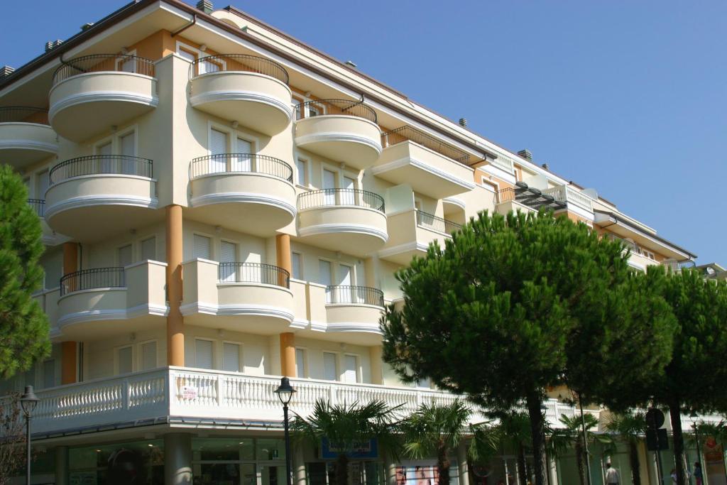 un grand bâtiment blanc avec des balcons et des arbres dans l'établissement Residence Il Tulipano, à Riccione