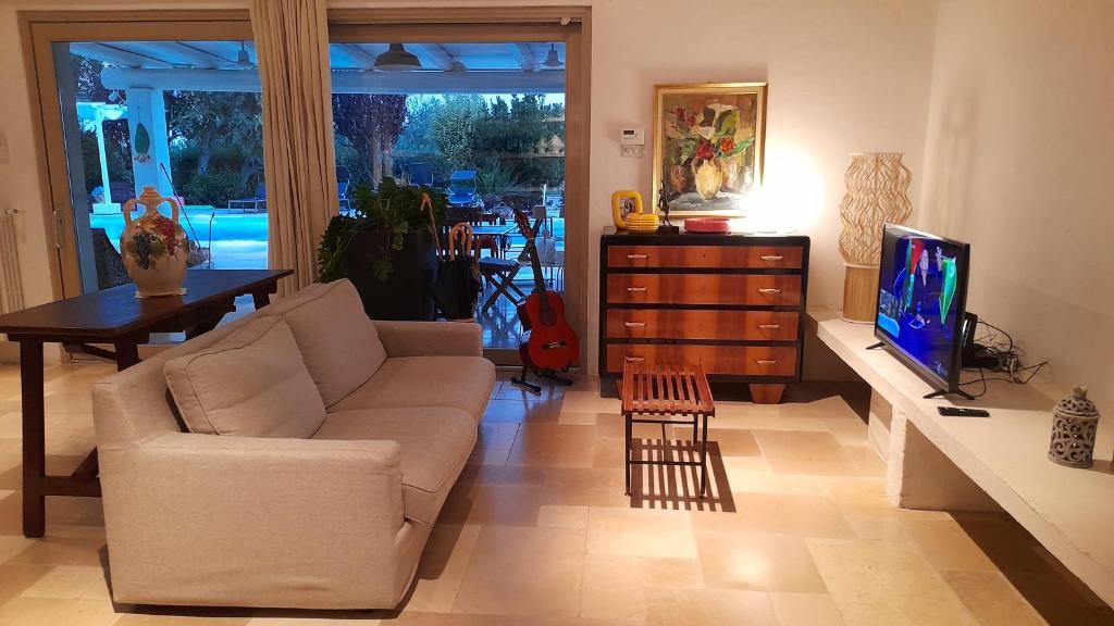 un salon avec un canapé et une télévision dans l'établissement Villa Poggio Fiorito, à Corato