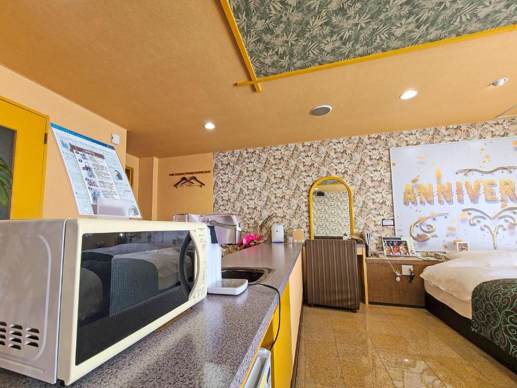 une cuisine avec un micro-ondes sur un comptoir à côté d'un lit dans l'établissement Pal Hotel Isahaya (Love Hotel), à Isahaya