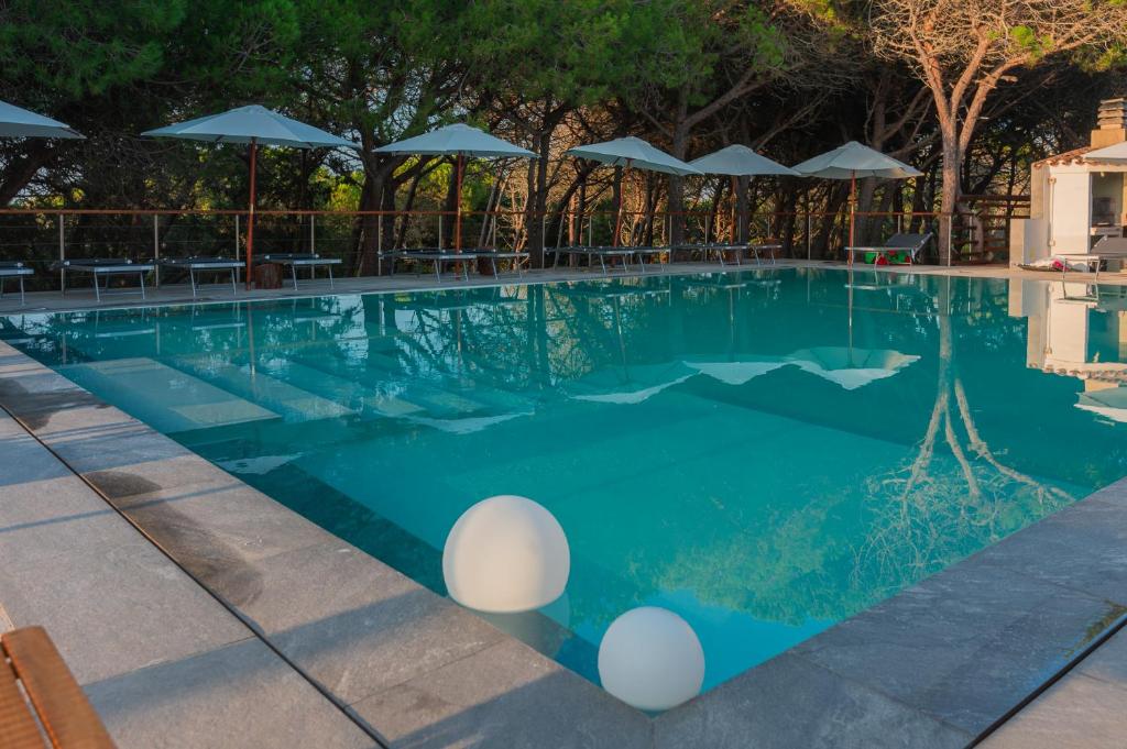 - une piscine d'eau bleue avec des parasols dans l'établissement Q Resort, à Marina di Sorso