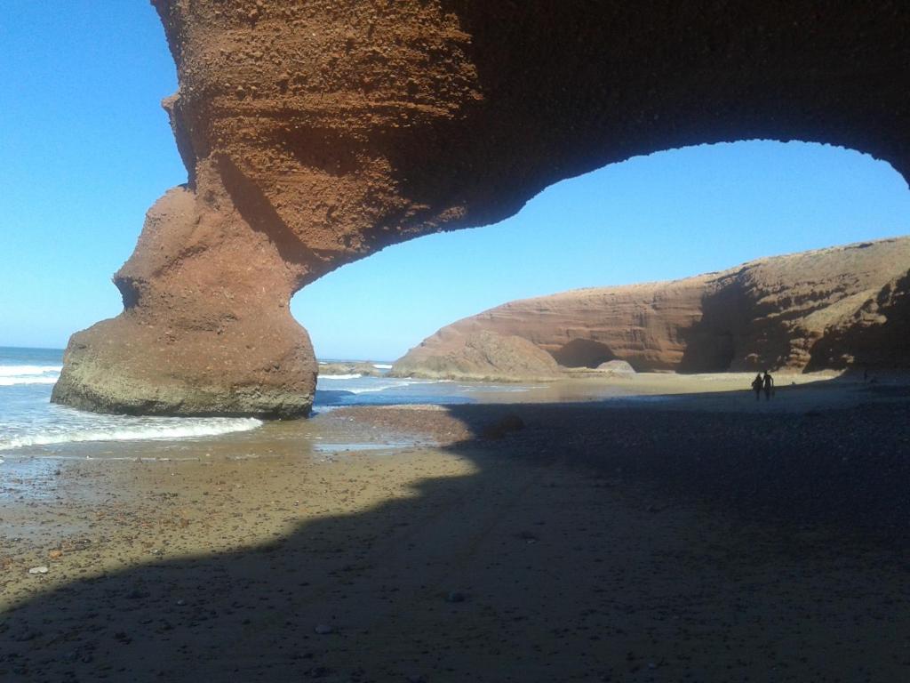 - une grotte sur la plage avec des personnes marchant sous celle-ci dans l'établissement Riad Le Lieu, à Tiznit