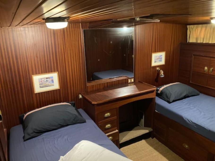 une chambre avec deux lits et un bureau dans un bateau dans l'établissement Bateau, à Marseilles-lès-Aubigny