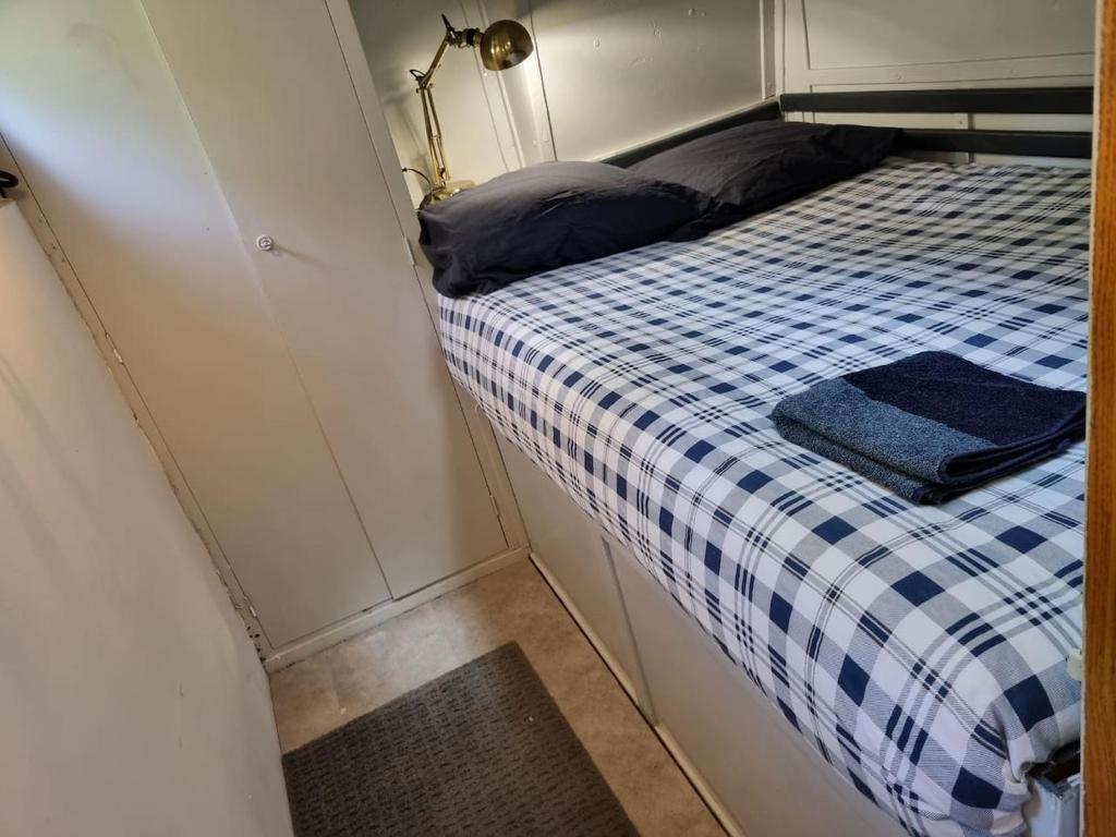 Cette petite chambre comprend un lit avec une couverture en damier bleu et blanc. dans l'établissement Péniche de charme avec jacuzzi sur canal du midi, à Toulouse