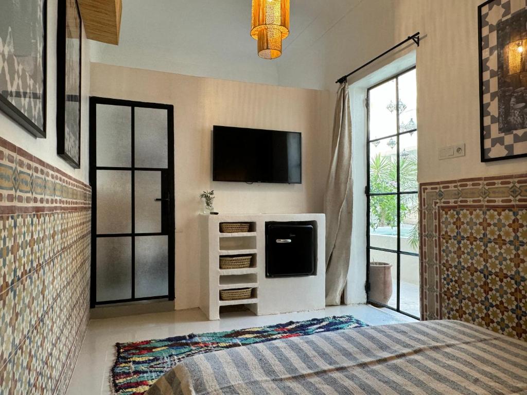 une chambre avec un lit et une télévision au mur dans l'établissement Riad Ait El Mouden, à Agadir