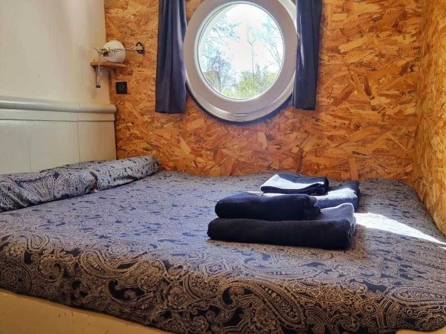 - un lit avec 2 oreillers et une fenêtre dans l'établissement Péniche Chaleureuse avec jacuzzi Toulouse centre, à Toulouse