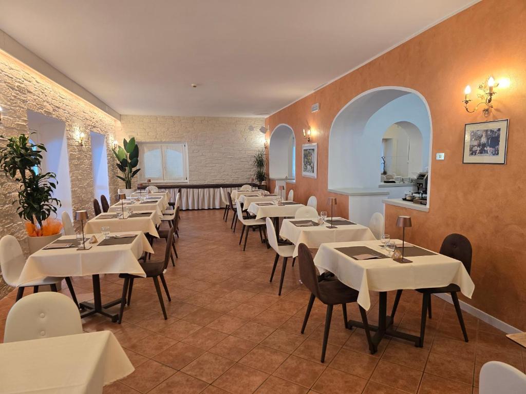 une salle à manger avec des tables et des chaises blanches dans l'établissement Lago Park Hotel, à Molveno