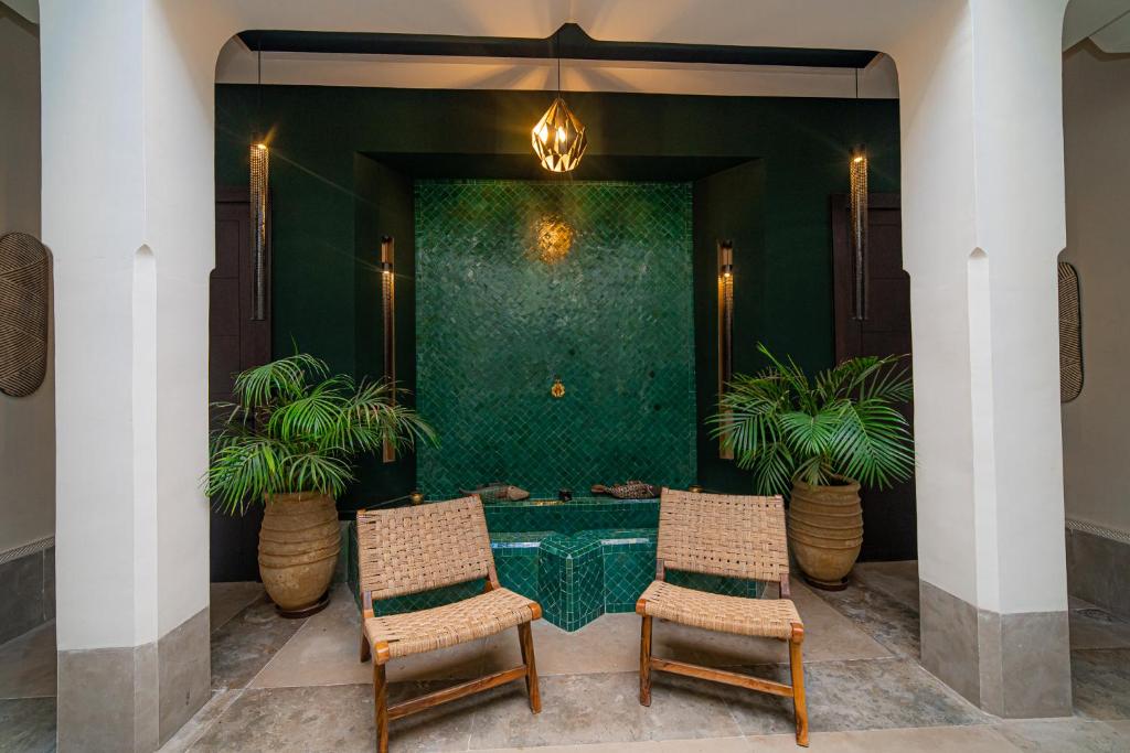 deux chaises devant un mur vert orné de plantes dans l'établissement Riad Sabrawa, à Marrakech