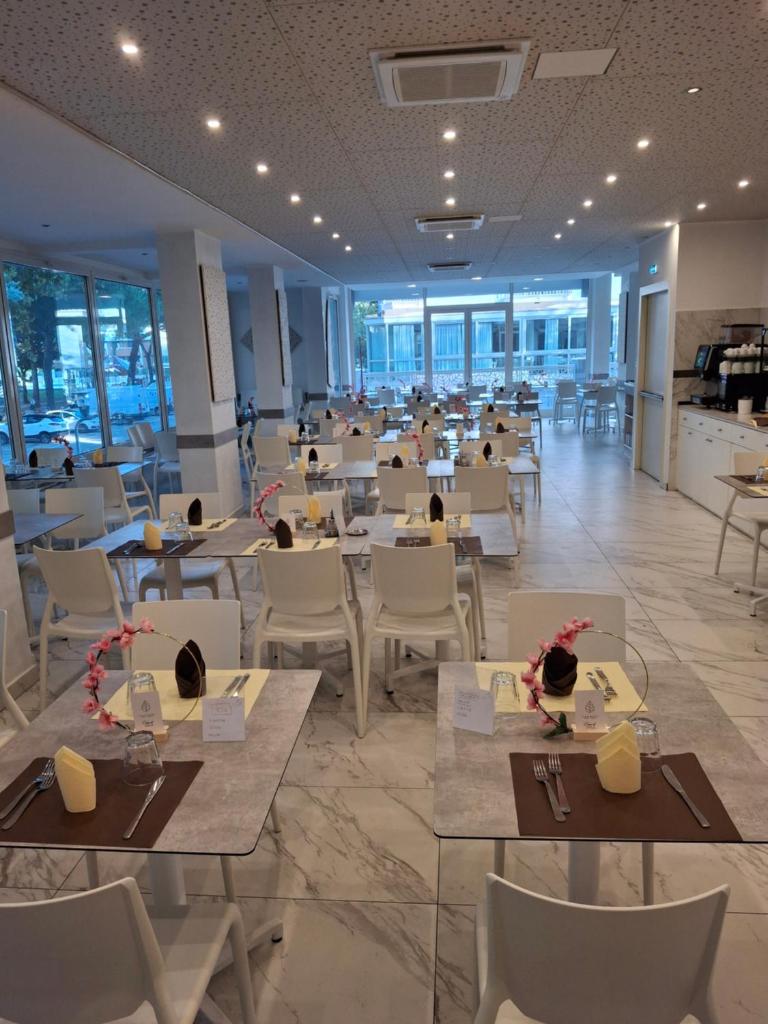 un restaurant avec des tables et des chaises dans une salle dans l'établissement Hotel Caravel Park, à Rimini 46 autres photos