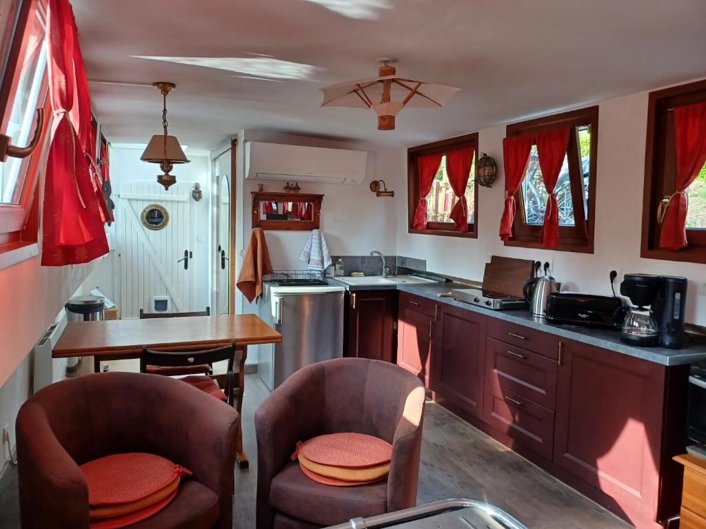 - une cuisine avec 2 chaises et une table dans l'établissement Sur la Somme à bord de la péniche Arche de Noé, à Pont-Rémy