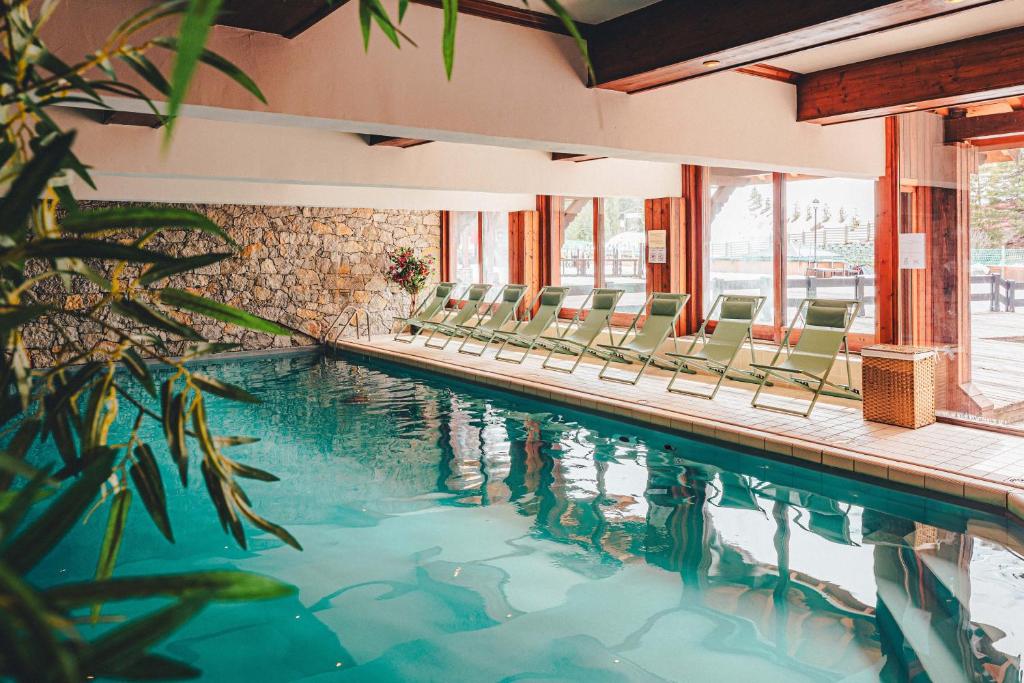 une piscine avec des chaises dans un immeuble dans l'établissement Hotel Mont Vallon, à Méribel