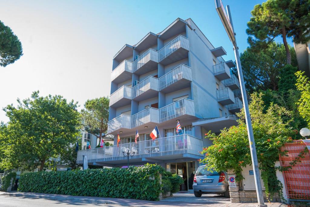 un immeuble bleu avec des drapeaux sur les balcons dans l'établissement Hotel Singapore, à Milano Marittima