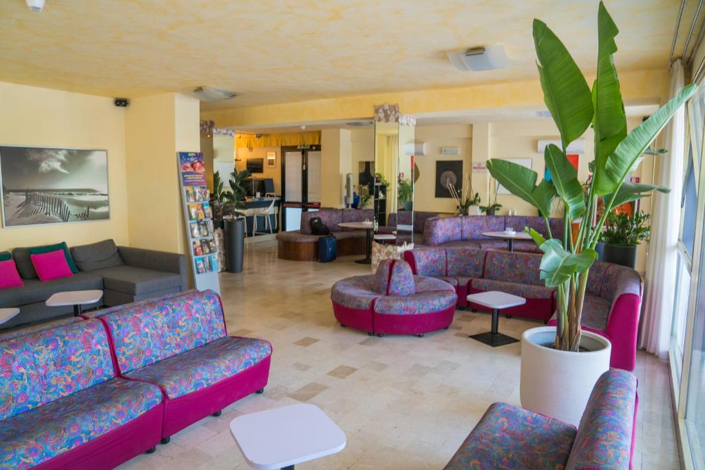 un salon avec des canapés et des tables violets dans l'établissement Hotel Singapore, à Milano Marittima