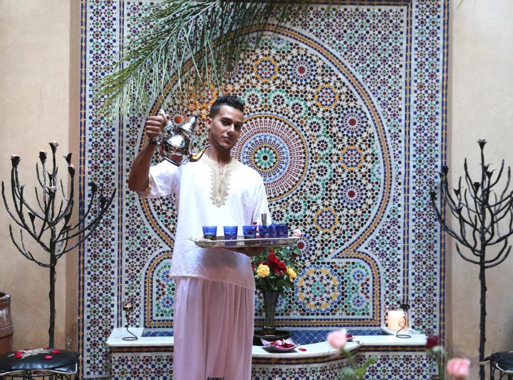 une femme debout devant un mur avec un bol dans l'établissement Samira Riads & Spa, à Marrakech