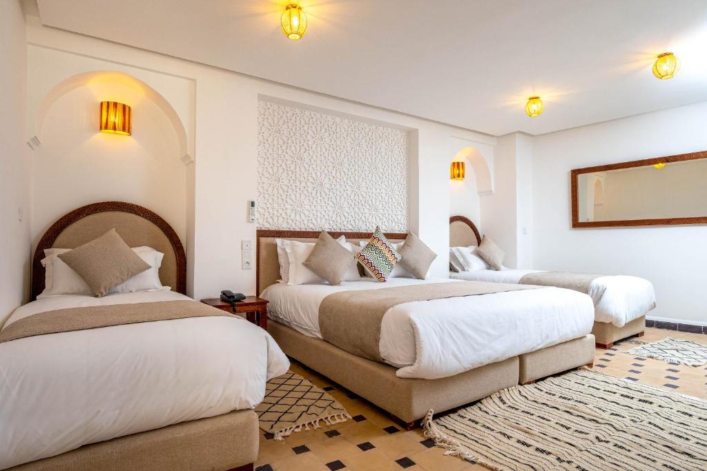 deux lits dans une chambre aux murs blancs dans l'établissement Riad Hamdane et SPA, à Marrakech