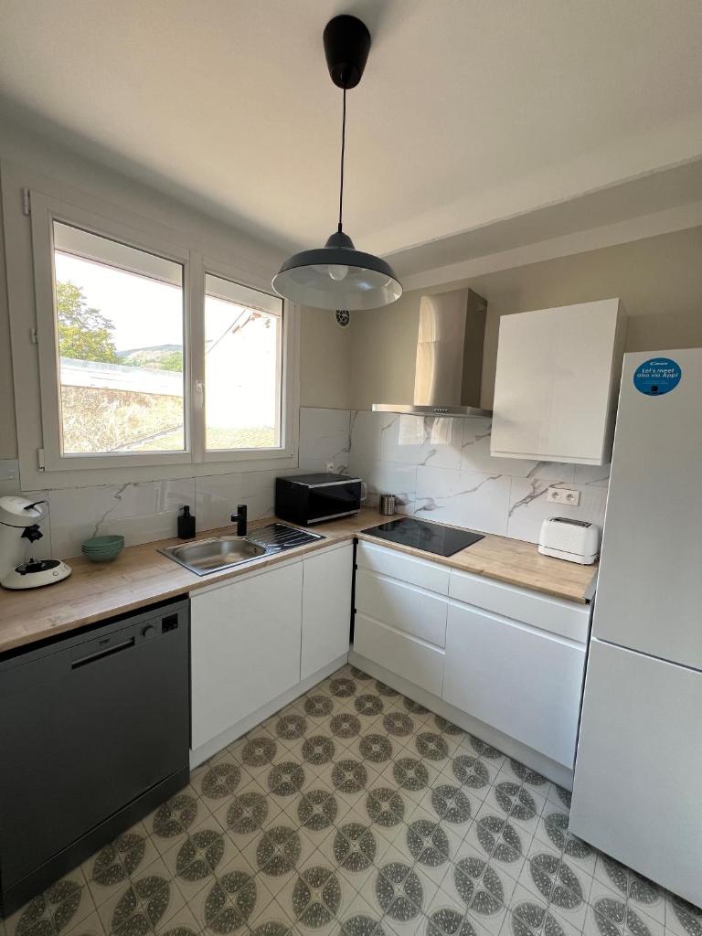 une cuisine avec des armoires blanches et un réfrigérateur blanc dans l'établissement Les Balcons du Couloubret, à Ax-les-Thermes 17 autres photos