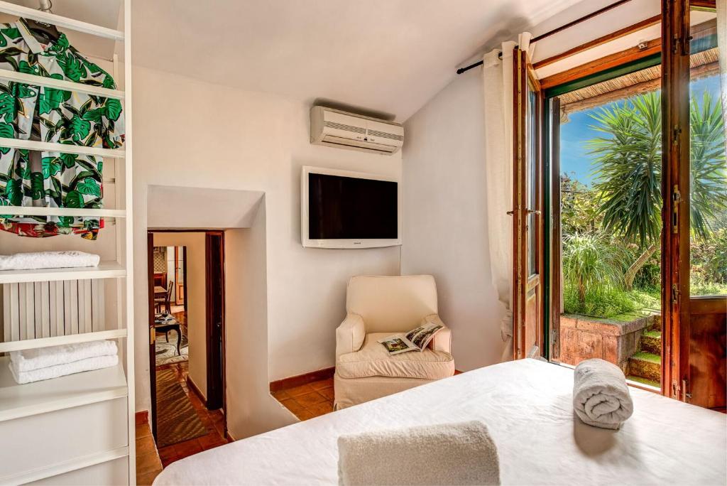 une chambre avec un lit, une chaise et une fenêtre dans l'établissement Villa Sorrentina With Panoramic Terrace, à Massa Lubrense