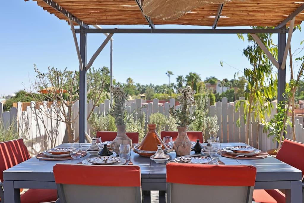 une table bleue avec des chaises rouges et des vases dessus dans l'établissement Riad dar Tayri, à Marrakech
