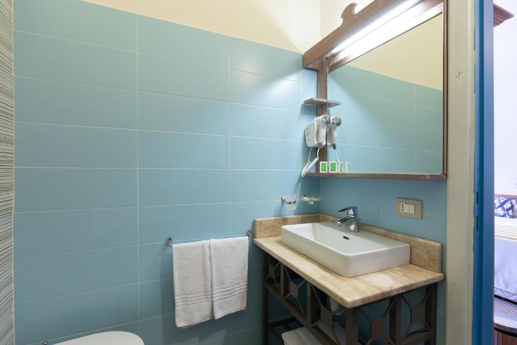 une salle de bain avec un lavabo et un miroir dans l'établissement MClub Budoni, à Budoni