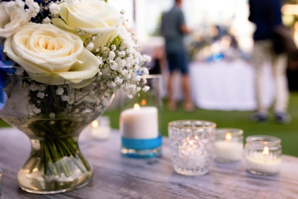 un vase avec des roses blanches et une bougie sur une table dans l'établissement Hotel Due Mari & SPA, à Rimini 236 autres photos