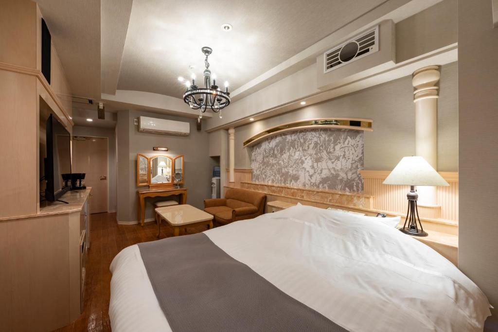 - une chambre avec un grand lit blanc et un lustre dans l'établissement Hotel Luna Sendai -Adult Only, à Shimo-ayashi