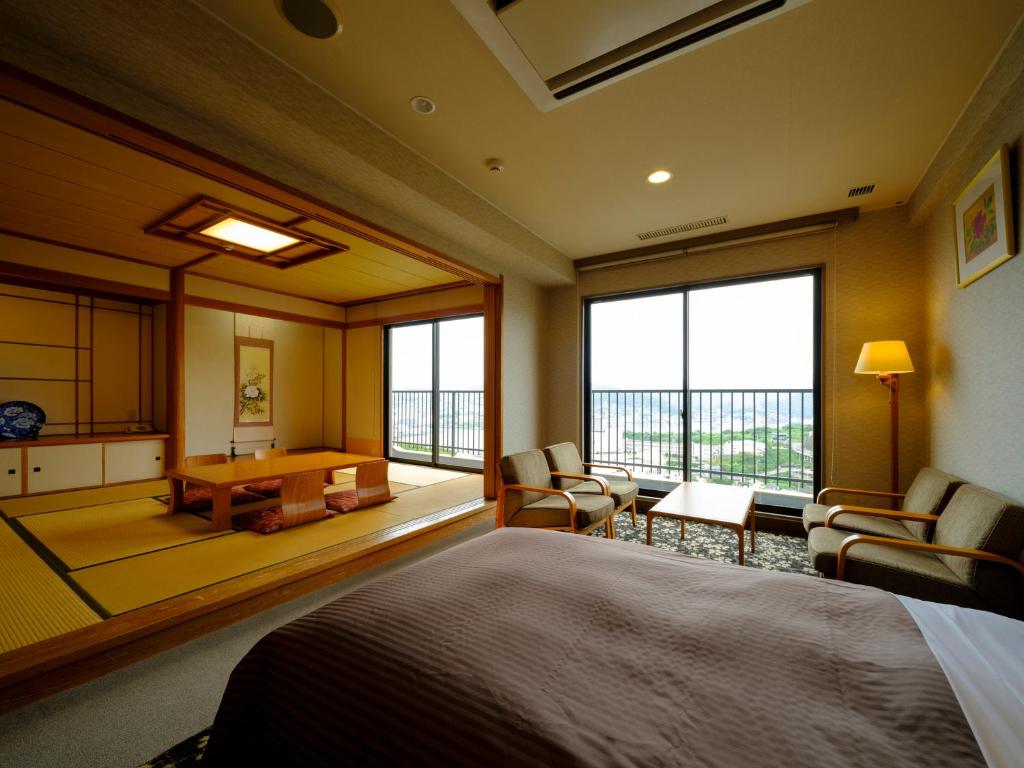 une chambre avec un lit, une table et des chaises dans l'établissement Inasayama Kanko Hotel, à Nagasaki