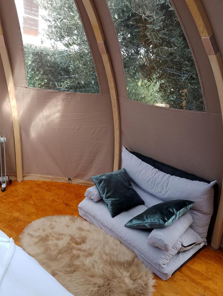 - un canapé avec des oreillers dans une chambre avec 2 fenêtres dans l'établissement Glamping Dôme, à Cagnes-sur-Mer 1 autre photo