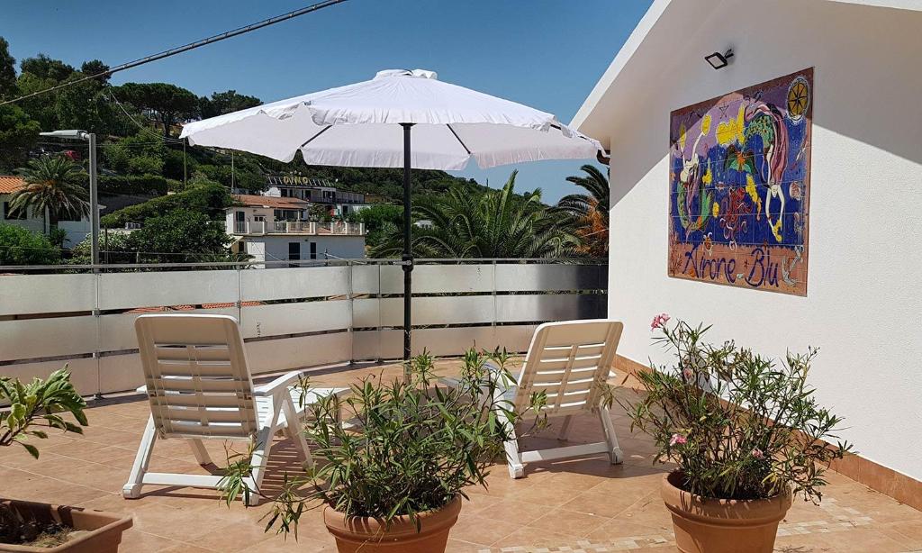 un patio avec deux chaises et un parasol dans l'établissement Hotel Stella Maris, à Capoliveri