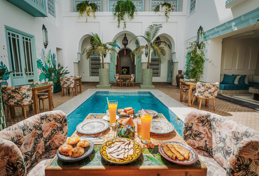 - une table avec de la nourriture et des boissons devant la piscine dans l'établissement Riad Assouel et Spa By La Siredrah, à Marrakech