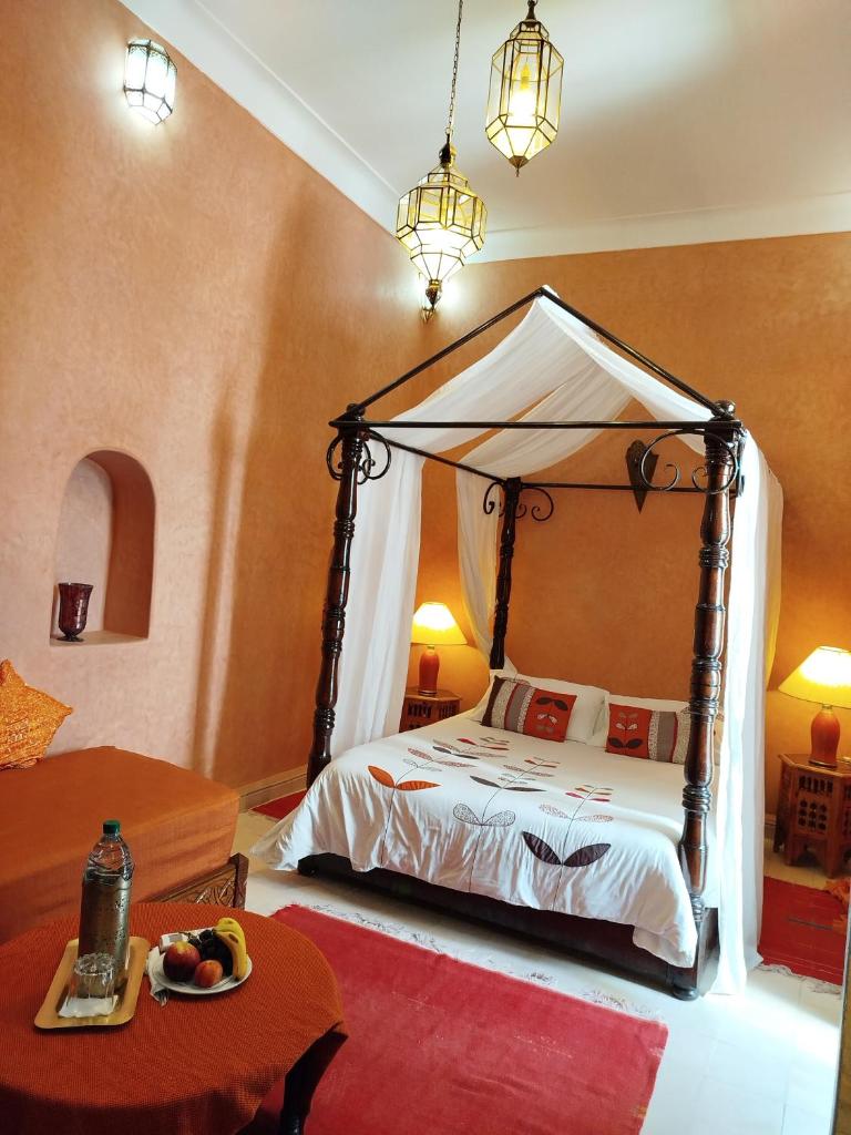 une chambre avec un lit à baldaquin et une table dans l'établissement Riad Les Trois Mages, à Marrakech