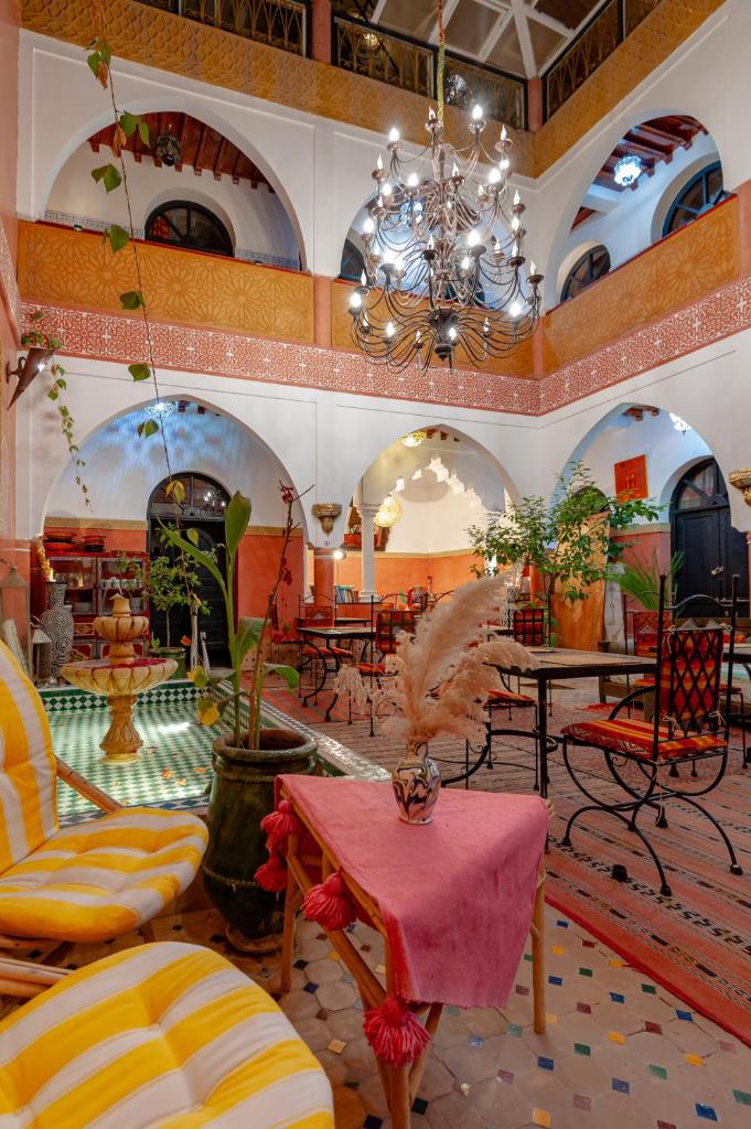 une grande pièce avec des tables, des chaises et un lustre dans l'établissement Riad Losra, à Marrakech