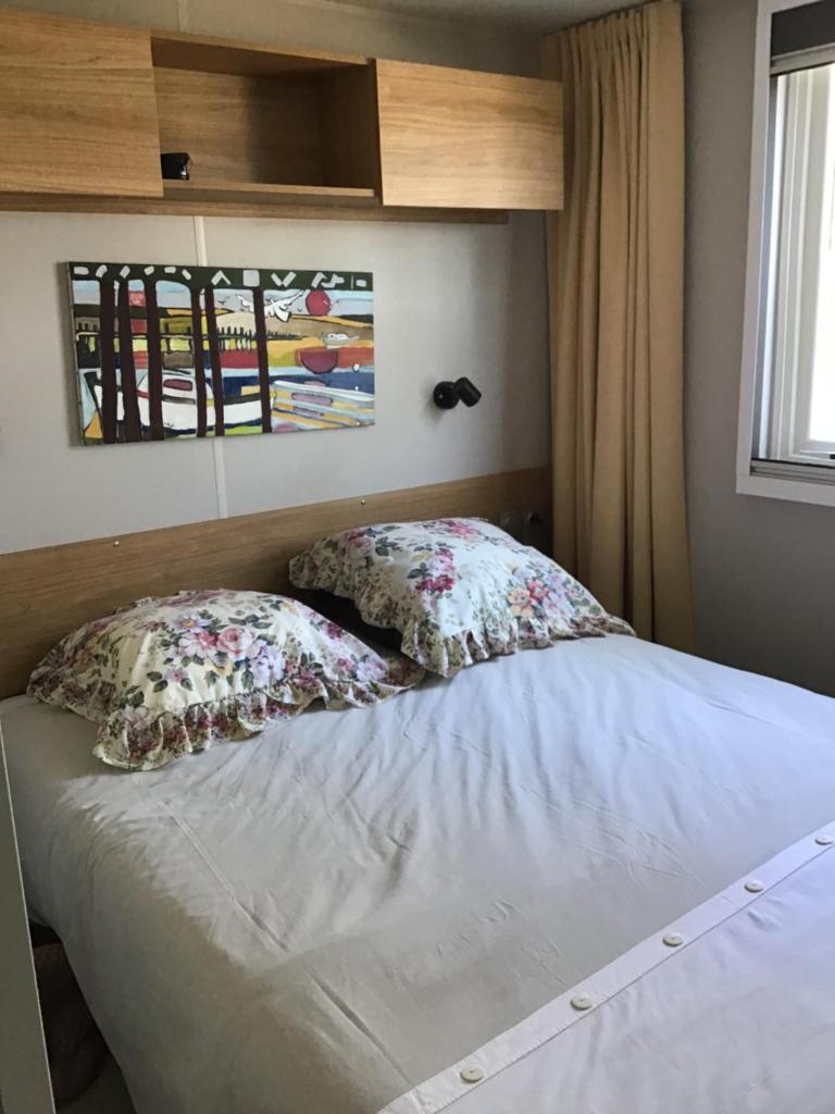 un lit avec deux oreillers dessus dans une chambre dans l'établissement MH 557 TOUT confort 40m2 3ch 2 sdb en lisière de forêt dans camping 4 étoiles, à Saint-Julien-en-Born
