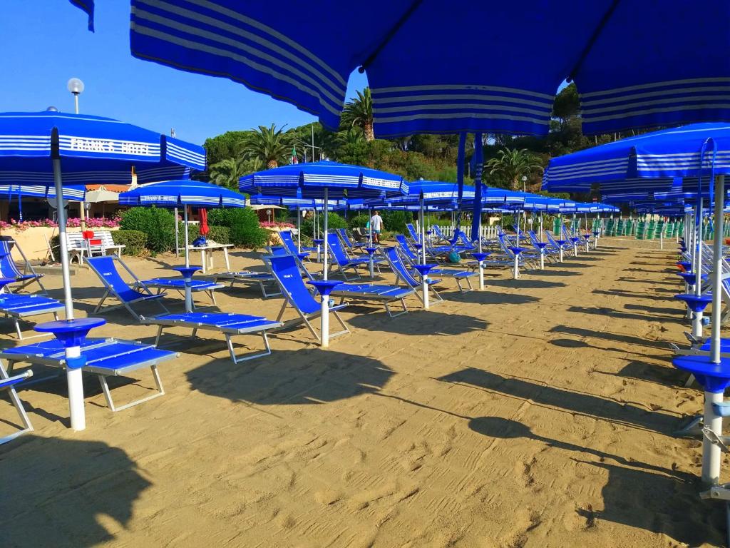 - une rangée de chaises et de parasols bleus sur une plage dans l'établissement Frank's Hotel, à Capoliveri