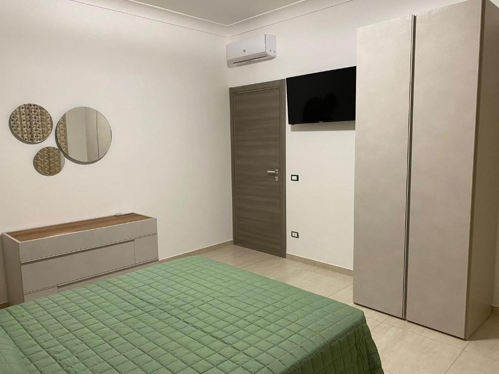 - une chambre avec un lit vert et une télévision dans l'établissement Giotera Village, à Sciacca