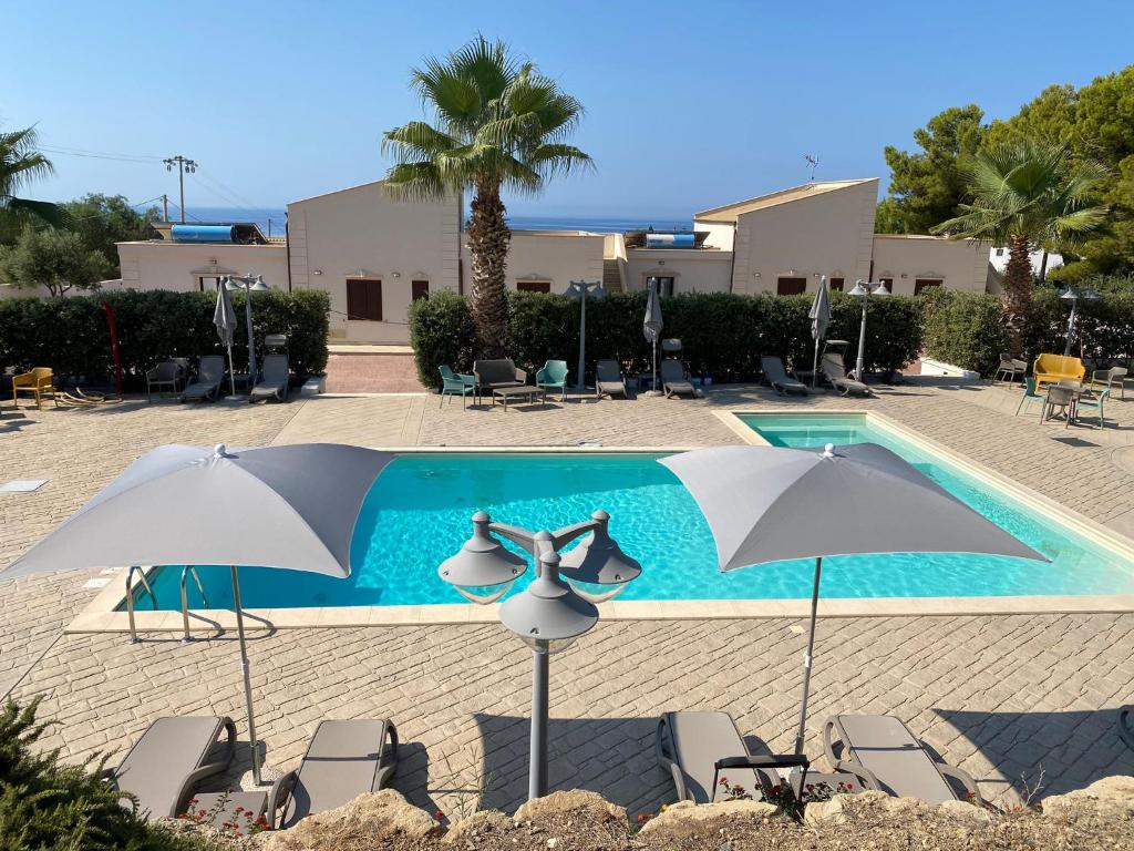 une piscine avec des chaises et des parasols en face de celle-ci dans l'établissement Giotera Village, à Sciacca