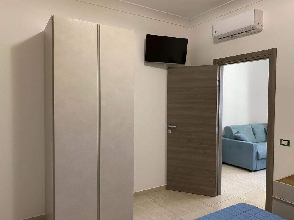 une porte coulissante dans une pièce avec un canapé bleu dans l'établissement Giotera Village, à Sciacca