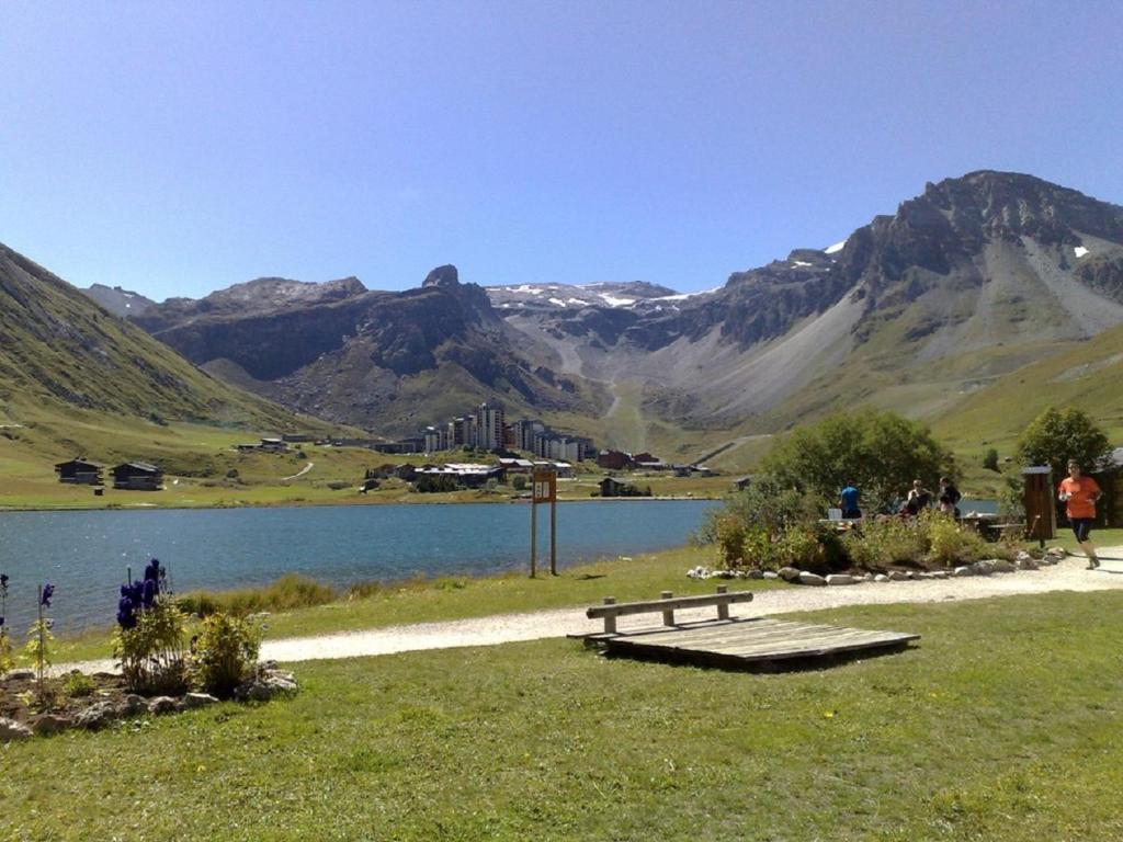 un banc à côté d'un lac avec des montagnes en arrière-plan dans l'établissement Studio 20 Les Grandes Platières, à Tignes