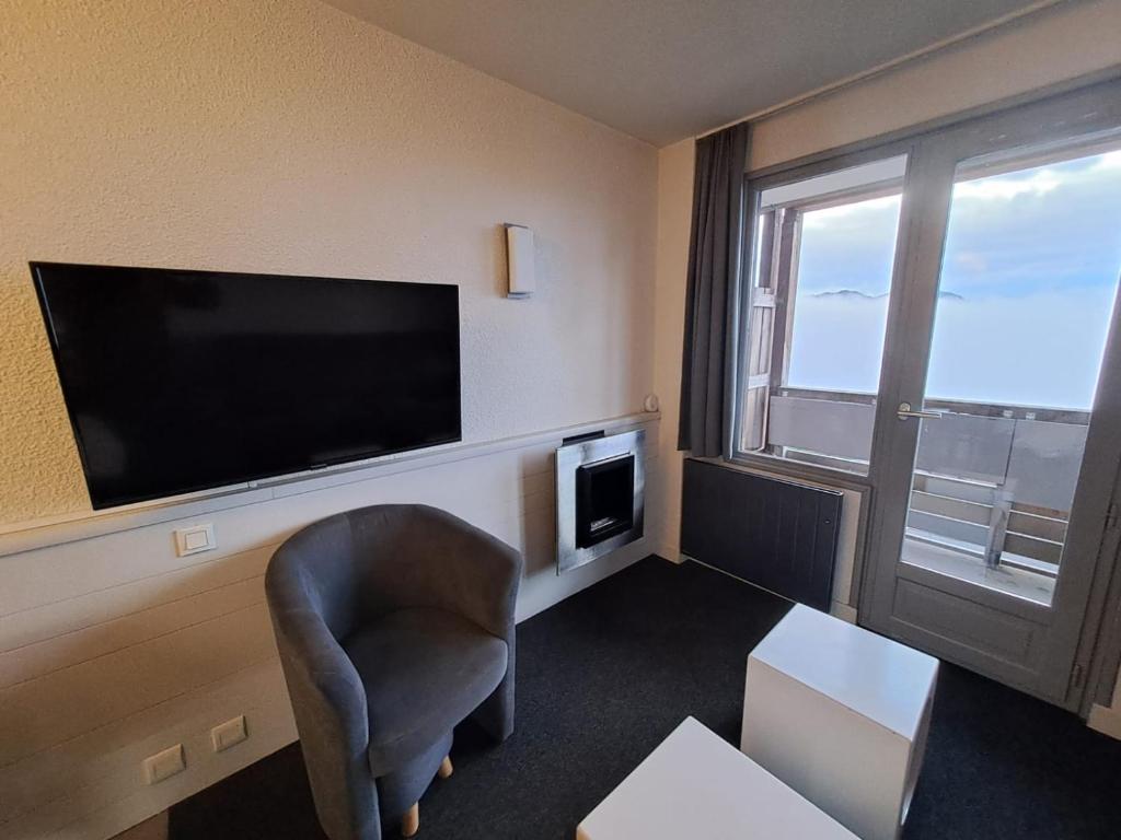 Il comprend un salon avec une chaise et une télévision à écran plat. dans l'établissement F2 résidence Antarès, à Avoriaz