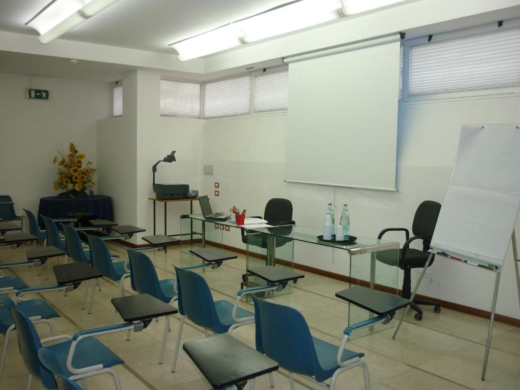 une salle de classe avec des bureaux, des chaises et un tableau blanc dans l'établissement Hotel Gala, à Pesaro
