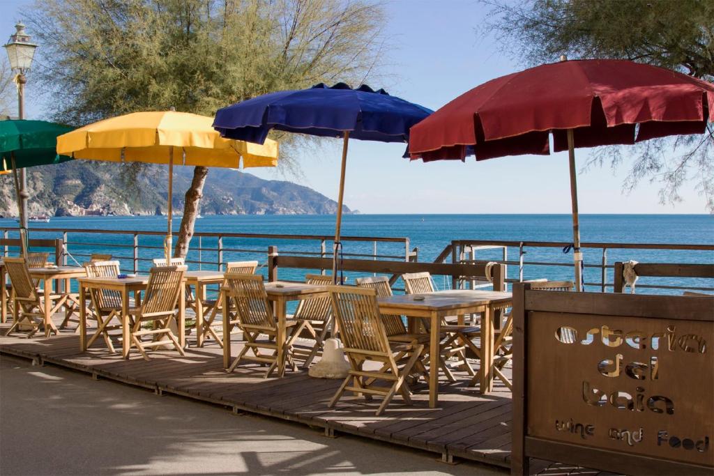 une rangée de tables et de chaises avec parasols dans l'établissement Hotel Baia, à Monterosso al Mare