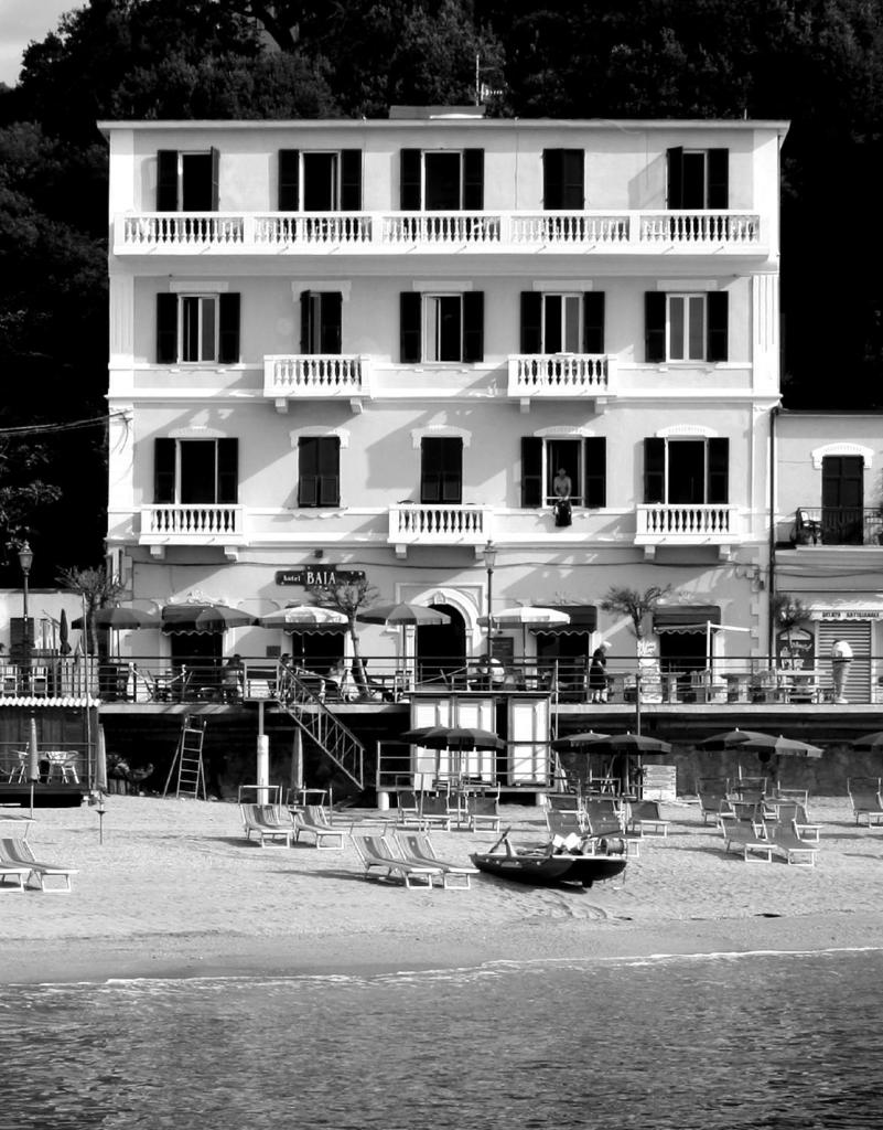 un grand bâtiment sur la plage avec un bateau dans l'eau dans l'établissement Hotel Baia, à Monterosso al Mare