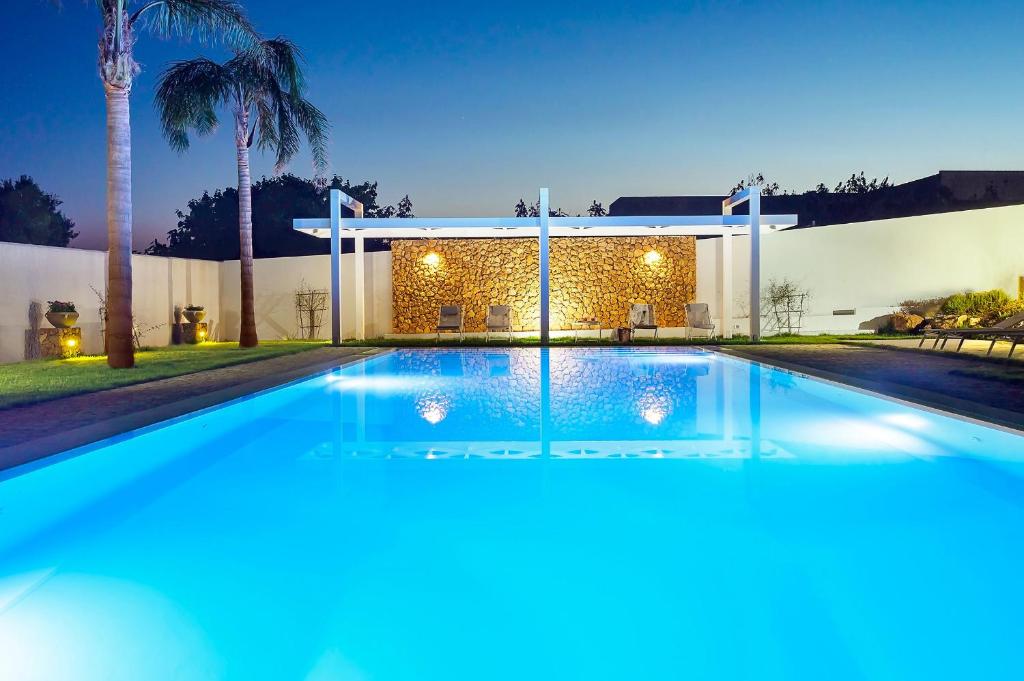 une piscine devant un immeuble avec des palmiers dans l'établissement Pietra del Sole, à Marausa