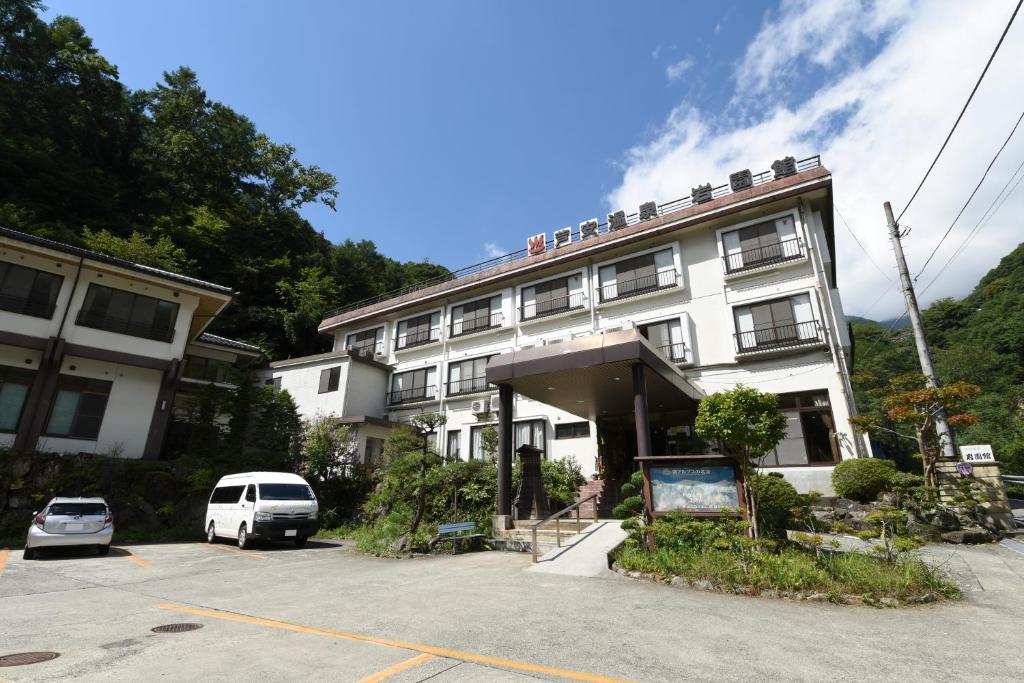 un bâtiment avec une voiture garée sur un parking dans l'établissement Iwazonokan, à Minami Alps