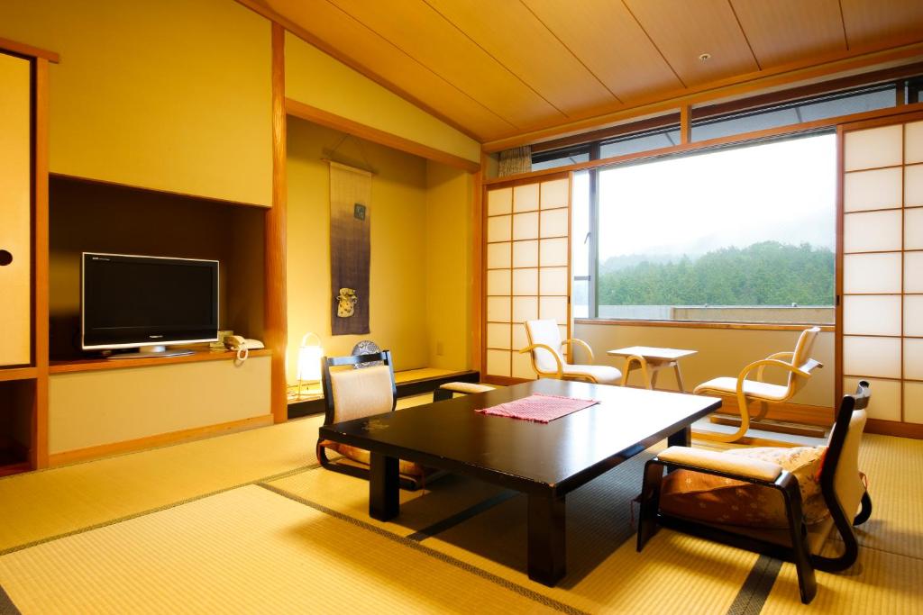 une pièce avec une table, des chaises et une télévision dans l'établissement Yumenoi, à Himeji