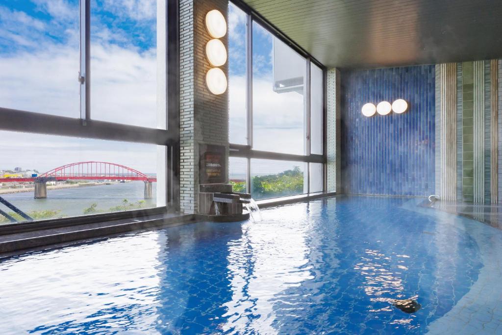 une grande piscine avec vue sur un pont dans l'établissement KAMENOI HOTEL Oarai, à Ōarai