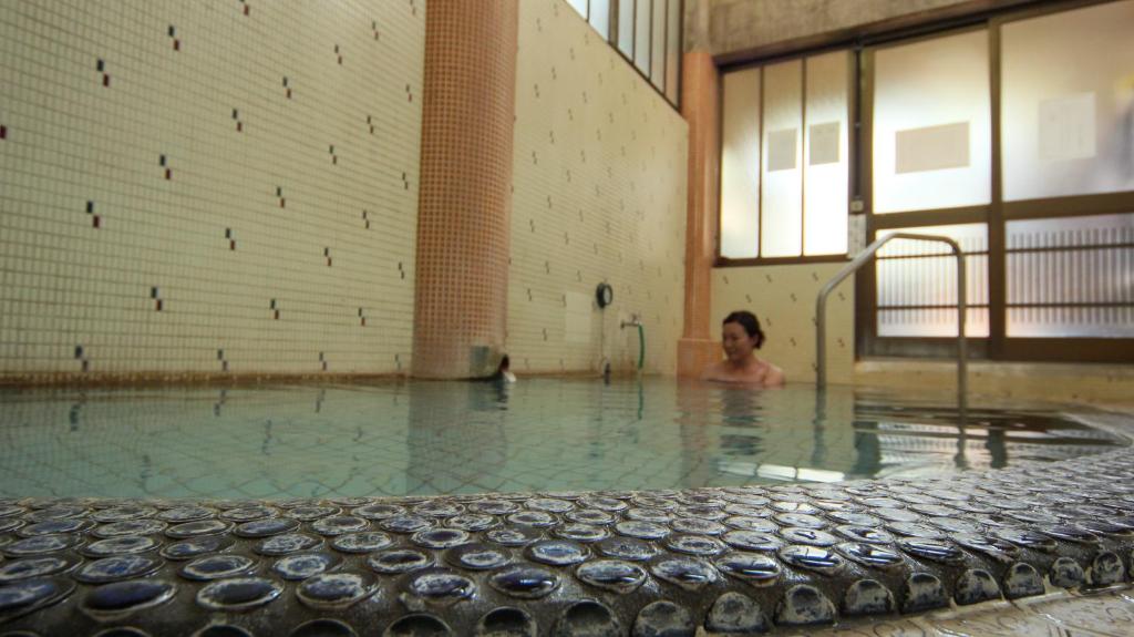 une femme est dans un bassin d'eau dans l'établissement Andaikan, à Yamanouchi