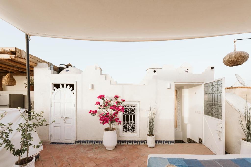 Cette chambre présente des murs blancs et des fleurs dans des vases blancs. dans l'établissement Riad Dar Alhambra, à Marrakech 37 autres photos