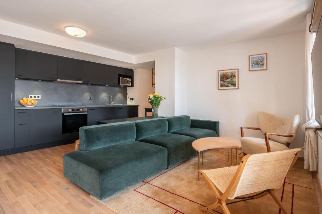 un salon avec un canapé vert et une cuisine dans l'établissement Apartment Bavella Alpe d'Huez - by EMERALD STAY, à Huez