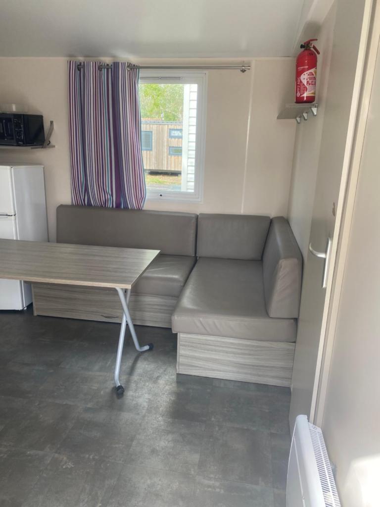 un salon avec un canapé et une table dans l'établissement Mobil home en Vendée, à Angles