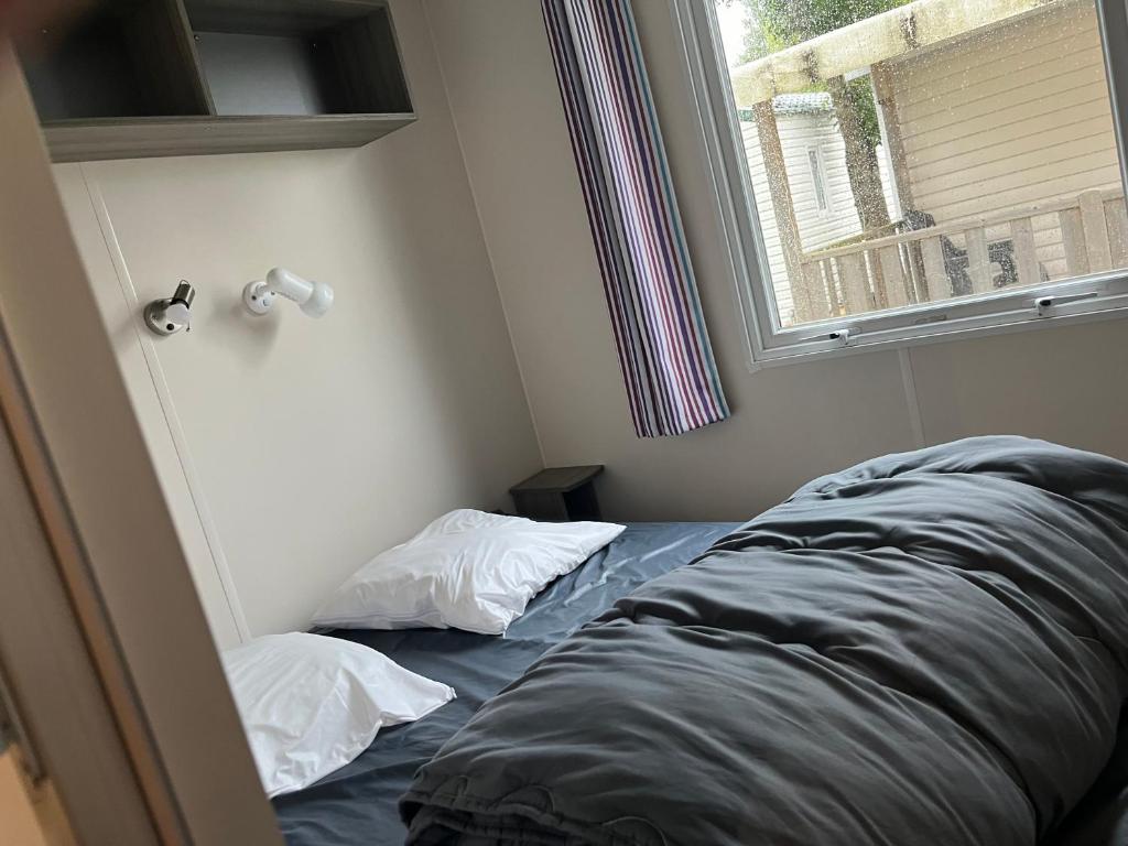 Cette chambre dispose de deux oreillers sur un lit à côté d'une fenêtre. dans l'établissement Mobil home en Vendée, à Angles